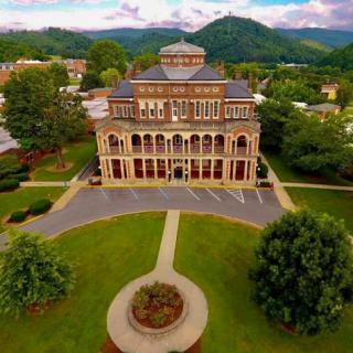 Aerial view of a beautifully designed historical building surrounded by lush greenery and mountains.