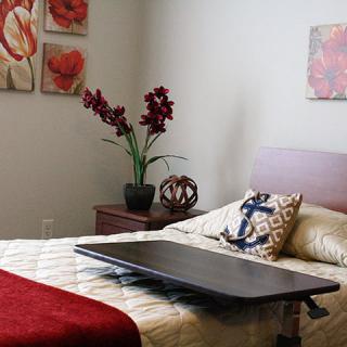A cozy bedroom with a neatly made bed, decorative pillows, and vibrant wall art.