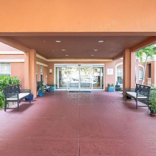 A covered building entrance with benches and potted plants.