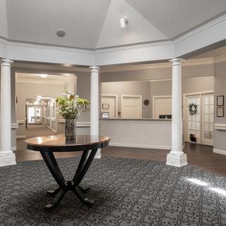 A spacious lobby area featuring a central table with a flower arrangement and surrounded by elegant columns.