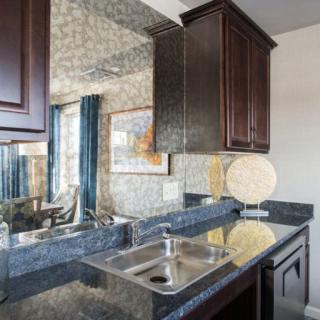 A modern kitchen interior featuring a sleek countertop with a sink, dark wooden cabinets, and a mirrored backsplash.