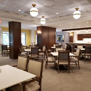 A spacious dining area with neatly arranged tables and chairs, featuring modern lighting fixtures.
