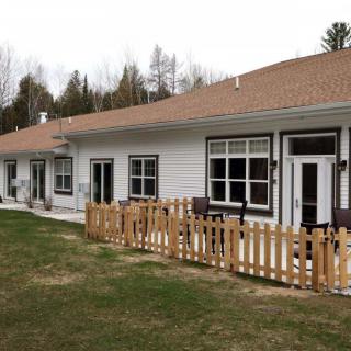 A row of single-story homes with a wooden fence and grassy lawn.