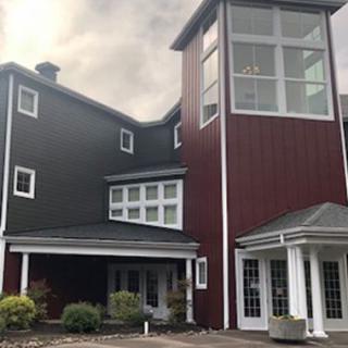 A modern residential building with a mix of dark and red exterior panels.