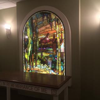 A beautifully crafted stained glass window set in a softly lit interior space.
