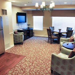 A cozy living room with a television, armchairs, and a dining table.
