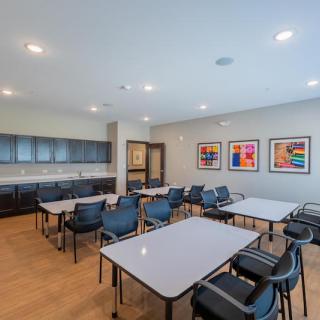 A modern meeting room with arranged tables, chairs, and colorful artwork on the walls.