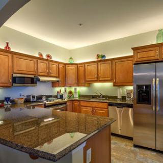 A beautifully designed modern kitchen featuring wooden cabinets, stainless steel appliances, and elegant granite countertops.