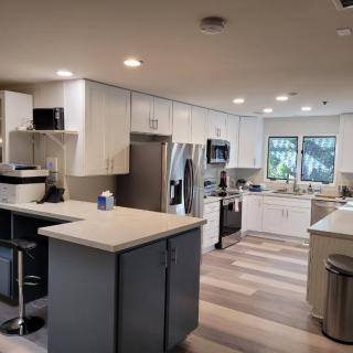 A modern kitchen with an island, white cabinets, and wood flooring.