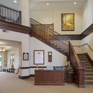 A spacious and elegant hotel lobby with a reception desk and wooden staircase.