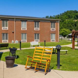 A sunny courtyard with a rocking chair and pathway in front of a brick building.