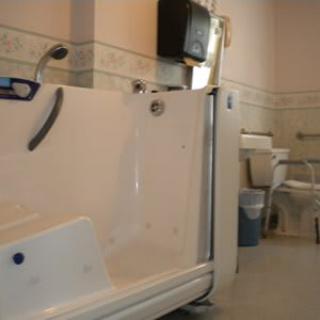 An accessible bathroom with a specialized bathtub designed for elderly or disabled individuals, featuring grab bars and safety enhancements.