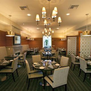 An elegantly designed restaurant dining room with chandeliers and neatly arranged tables and chairs.