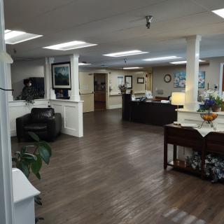 A spacious office lobby with a wooden floor, featuring a reception desk and comfortable seating.