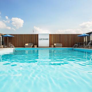 A serene outdoor swimming pool with deck chairs and sun umbrellas under a clear blue sky.