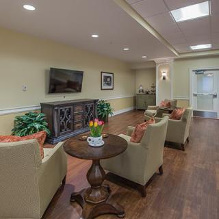 A cozy living room with comfortable chairs, a TV, and decorative plants.
