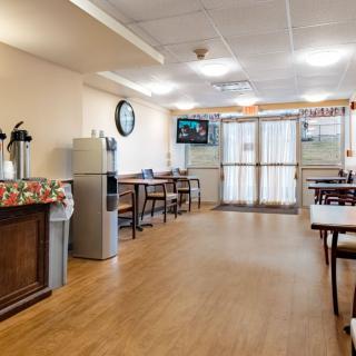 A cozy indoor dining area with tables, chairs, a television, and a coffee station.
