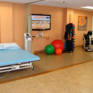 A physical therapy room equipped with a treatment table, therapy balls, and exercise machines.