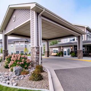 A view of a building entrance with landscaped surroundings and a driveway.