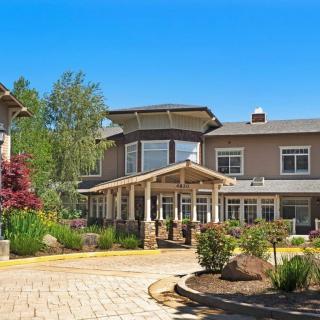 Exterior of a residential building with a landscaped garden and driveway on a sunny day.