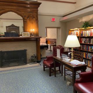 A cozy library corner featuring bookshelves, a fireplace, and comfortable seating.
