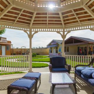 A cozy outdoor seating area under a gazebo, overlooking a well-maintained garden on a sunny day.