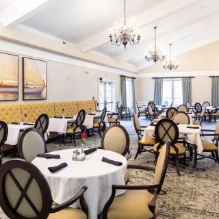 An elegant dining room with neatly arranged tables and chairs, featuring chandeliers and decorative artwork.