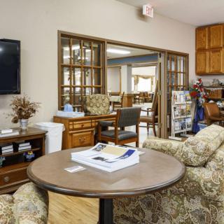 A cozy living room with comfortable sofas, a round table with magazines, and a television mounted on the wall.