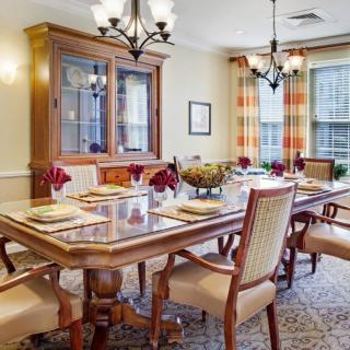 A well-appointed dining room with a large table set for a meal, complemented by elegant chairs and lighting.