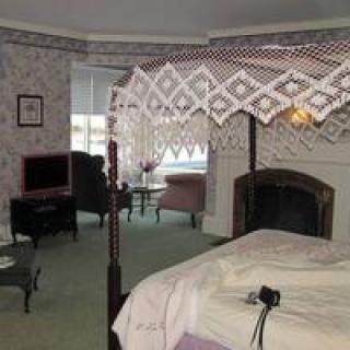 A traditional bedroom interior with a cozy fireplace and elegant furnishings.