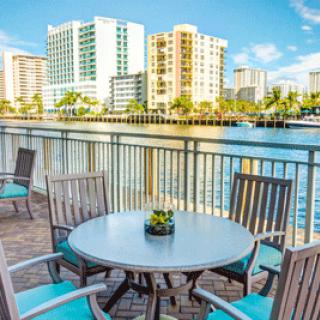 A scenic view of a waterfront patio overlooking tall city buildings under a clear blue sky.