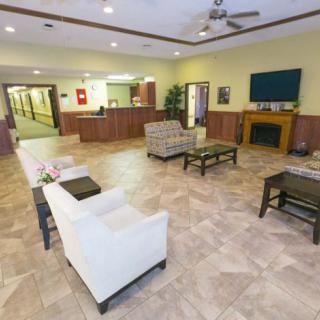 A spacious lobby area featuring comfortable seating, a reception desk, and a television mounted above a fireplace.