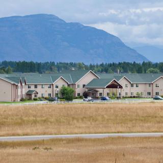 A row of residential buildings set against a mountainous backdrop with open fields in the foreground.