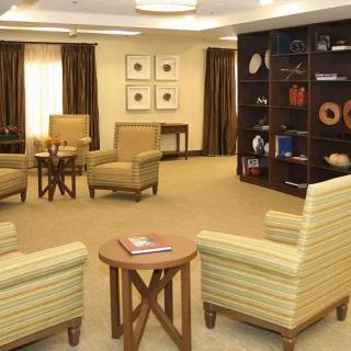 A cozy living room with comfortable chairs, a wooden table, and decorative shelves.