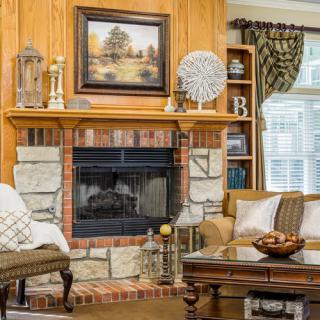 A cozy living room featuring a brick and stone fireplace, surrounded by comfortable furniture and elegant decorations.
