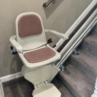 A stairlift installed on a residential staircase, designed to assist with mobility and accessibility.
