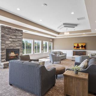 A modern living room featuring comfortable seating, a stone fireplace, and large windows providing natural light.