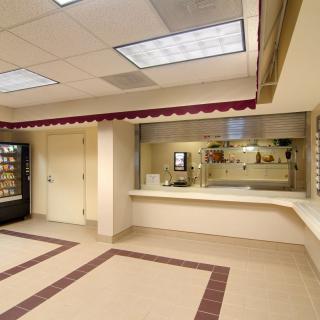 An empty cafeteria with a vending machine and serving counter.