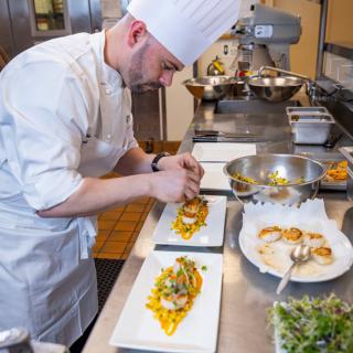 A chef meticulously plating a gourmet dish in a professional kitchen.