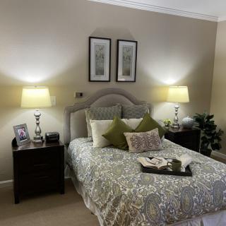 A cozy bedroom with elegant decor, featuring a neatly made bed, decorative pillows, and soft lighting from matching lamps on nightstands.