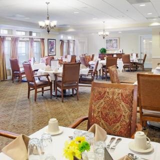 A well-appointed dining room with neatly arranged tables and chairs, featuring elegant table settings and a warm ambiance.