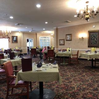 A restaurant dining room with neatly arranged tables and chairs under a chandelier.