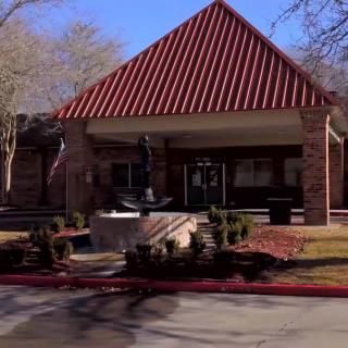 A brick building with a red roof and landscaped entrance.