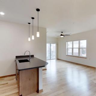 A spacious and modern open-concept kitchen and living room area, featuring sleek pendant lighting and ample natural light.