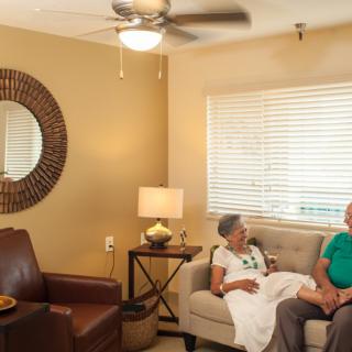 Two people sit on a sofa in a cozy living room, engaged in conversation.