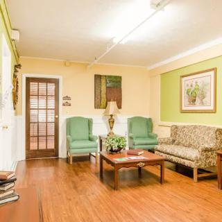 A cozy living room with a sofa, armchairs, and a coffee table arranged on wooden flooring with decorative wall art and lamp.