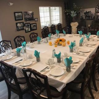 A formal dining table set with neatly arranged napkins and place settings in a well-decorated room.