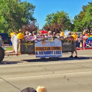 A vibrant parade featuring a banner promoting assisted living and memory care services.