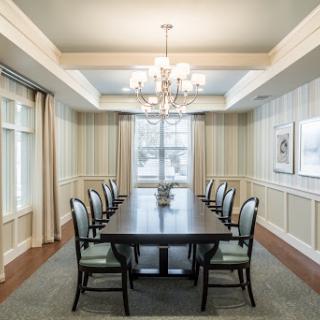 A beautifully designed dining room featuring a long wooden table and elegant chandelier, complemented by stylish chairs and soft natural lighting.