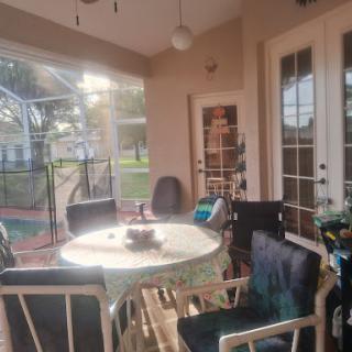 A cozy patio area illuminated by warm sunlight, featuring a round table and comfortable chairs.